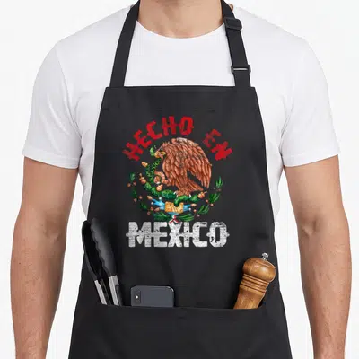 Tablier de cuisine noir avec aigle tenant un serpent sur cactus et texte Hecho en Mexico.
