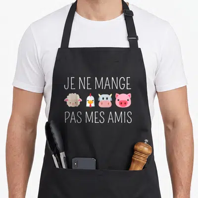 Tablier de cuisine noir avec le texte Je ne mange pas mes amis surplombant quatre têtes d'animaux colorées et stylisées.