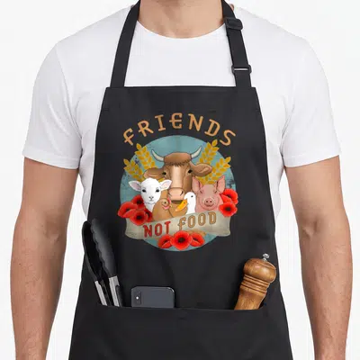 Tablier de cuisine noir avec illustration d'animaux et texte Friends Not Food entouré de fleurs rouges.