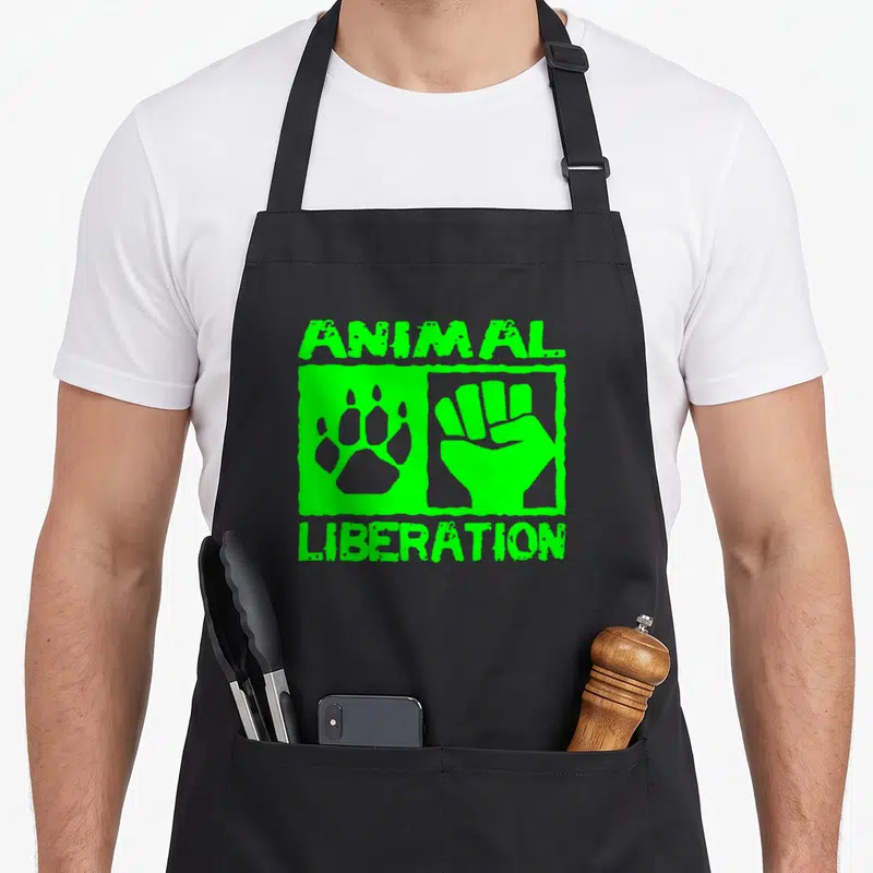 Tablier de cuisine noir avec inscription Animal Liberation verte, poing et patte d'animal stylisés au centre du design graphique.