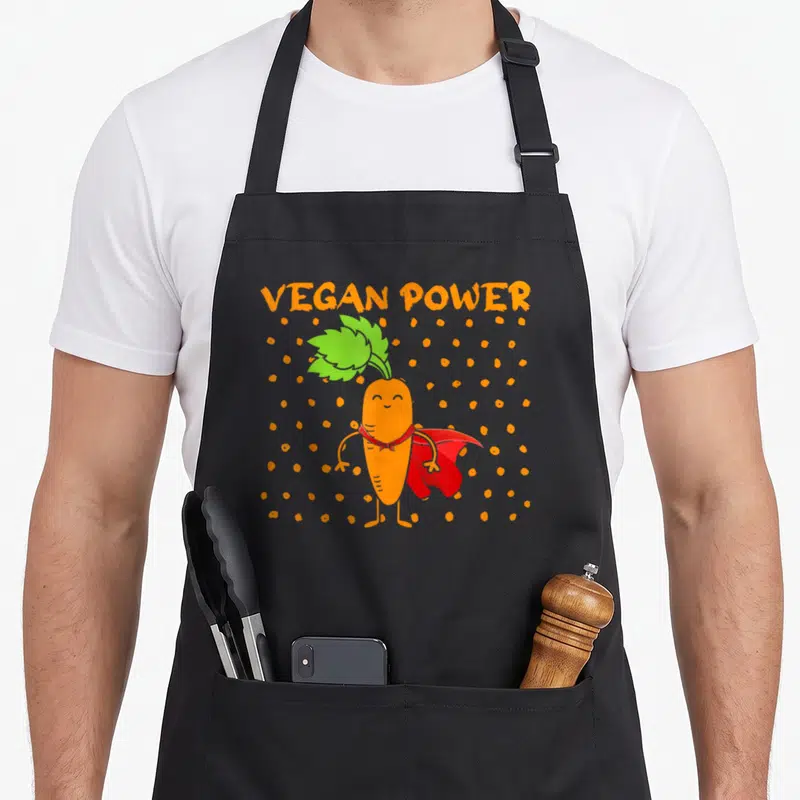 Tablier de cuisine noir avec illustration d'une carotte super-héros orange et cape rouge.