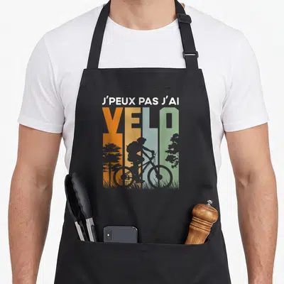 Tablier de cuisine noir avec silhouette de cycliste et texte J'peux pas j'ai vélo en lettres colorées.