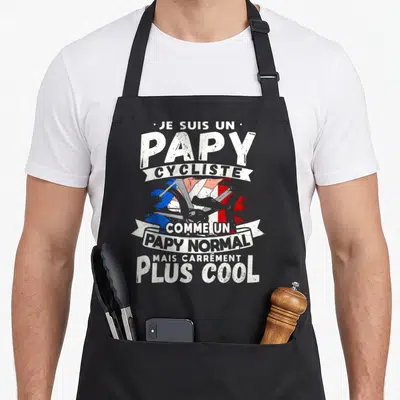 Tablier de cuisine noir avec inscription Je suis un papy cycliste et illustration de roue de vélo sur fond tricolore.