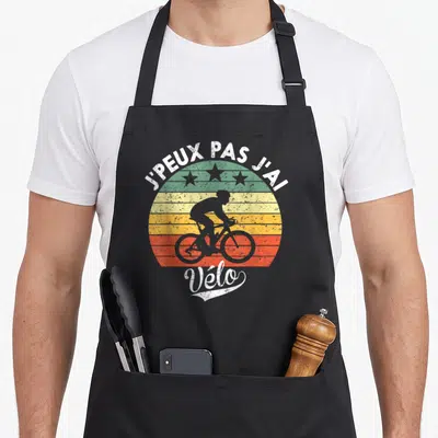 Tablier de cuisine noir avec silhouette de cycliste sur fond rayé coloré et texte J'peux pas j'ai vélo