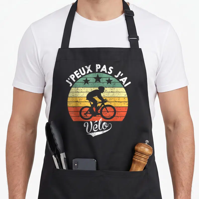 Tablier de cuisine noir avec silhouette de cycliste sur fond rayé coloré et texte J'peux pas j'ai vélo
