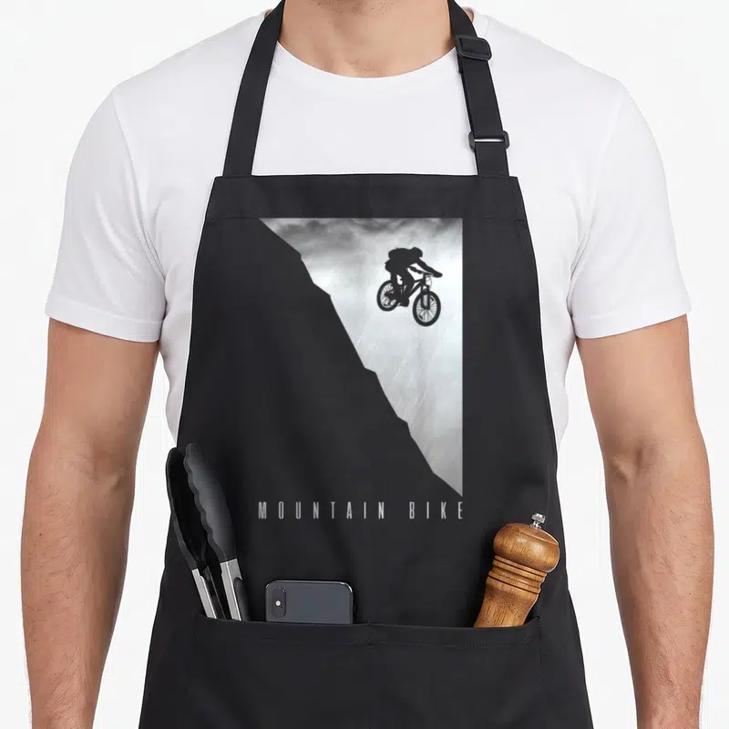 Tablier de cuisine noir avec silhouette cycliste en saut et texte MOUNTAIN BIKE en bas.
