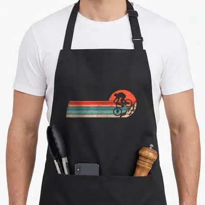 Tablier de cuisine noir avec illustration rétro d'un cycliste sur fond de rayures colorées et de soleil orange.