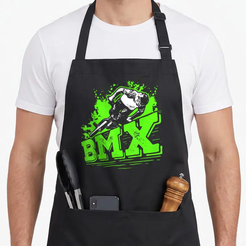 Tablier de cuisine noir avec illustration d'un cycliste BMX effectuant un saut au-dessus du texte BMX vert fluorescent.