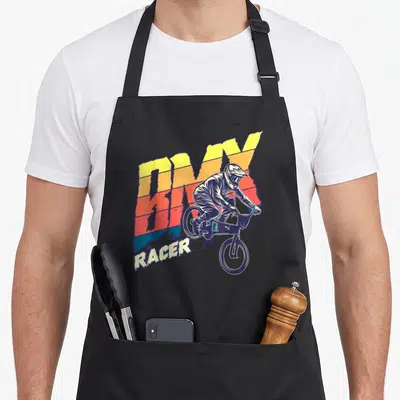 Tablier de cuisine noir avec illustration colorée d'un cycliste BMX Racer en action sur fond dégradé.
