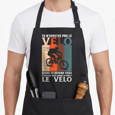 Tablier de cuisine noir avec silhouette cycliste vintage et texte humoristique sur fond de bandes colorées délavées.