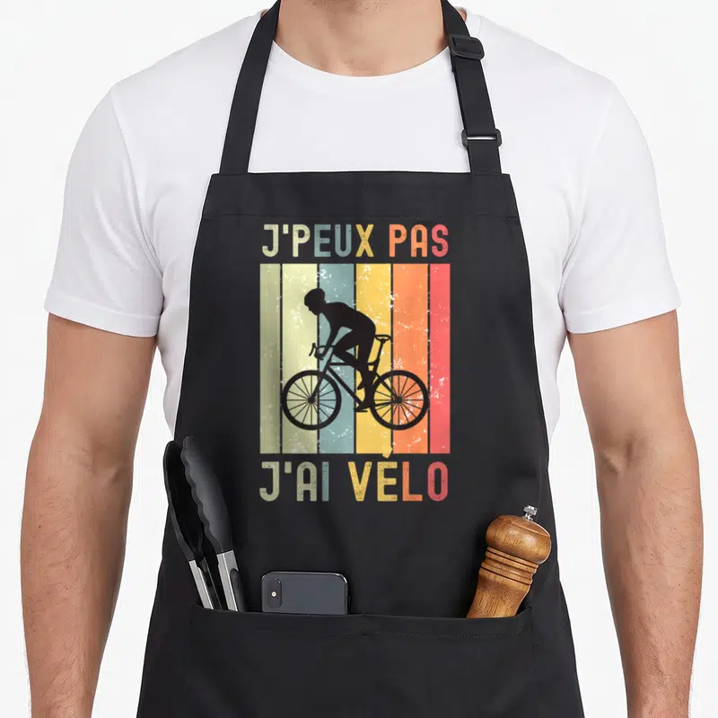 Tablier de cuisine noir avec silhouette cycliste et texte J'peux pas j'ai vélo sur fond rayé vintage.