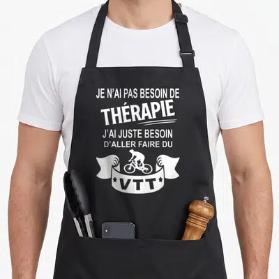 Tablier de cuisine noir avec texte blanc et silhouette cycliste VTT sur un ruban décoratif.