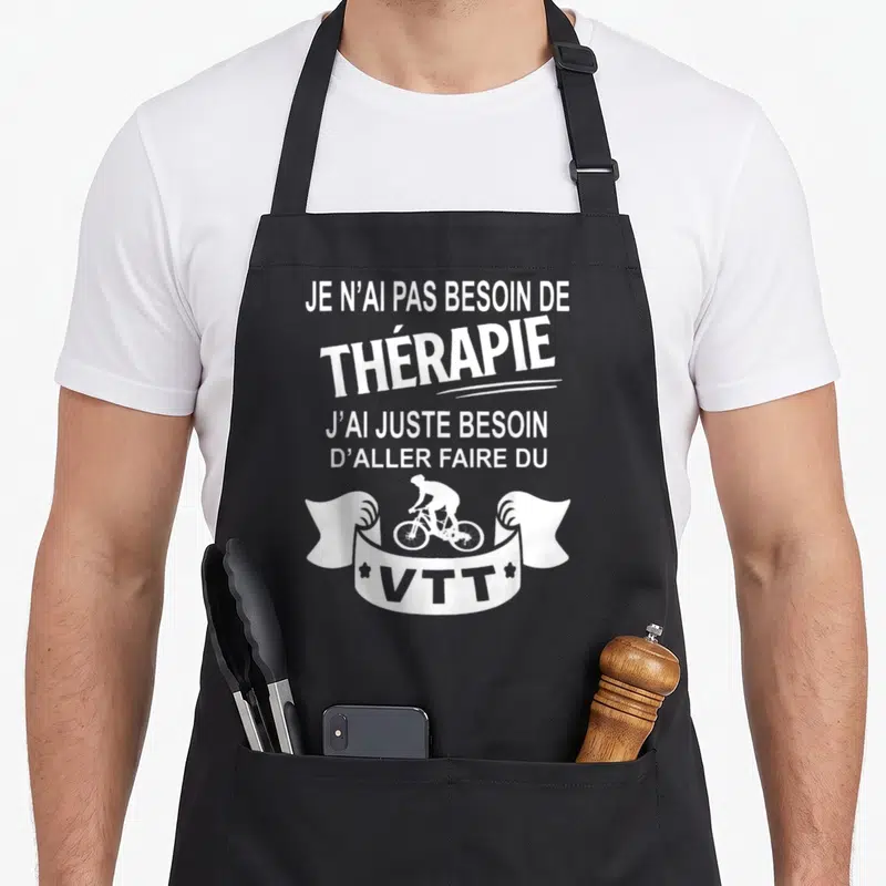 Tablier de cuisine noir avec texte blanc et silhouette cycliste VTT sur un ruban décoratif.