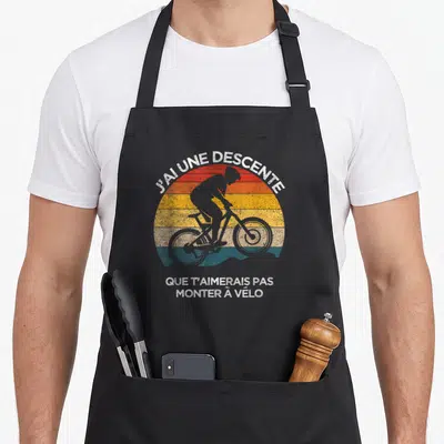 Tablier de cuisine noir avec silhouette cycliste et texte J'ai une descente que t'aimerais pas monter à vélo sur fond rayé coloré.
