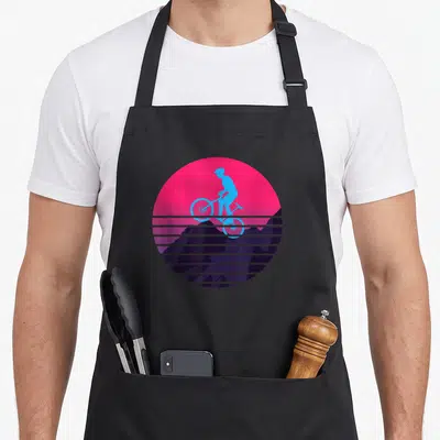Tablier de cuisine noir avec silhouette cycliste bleue sur fond rose et montagnes violettes striées.