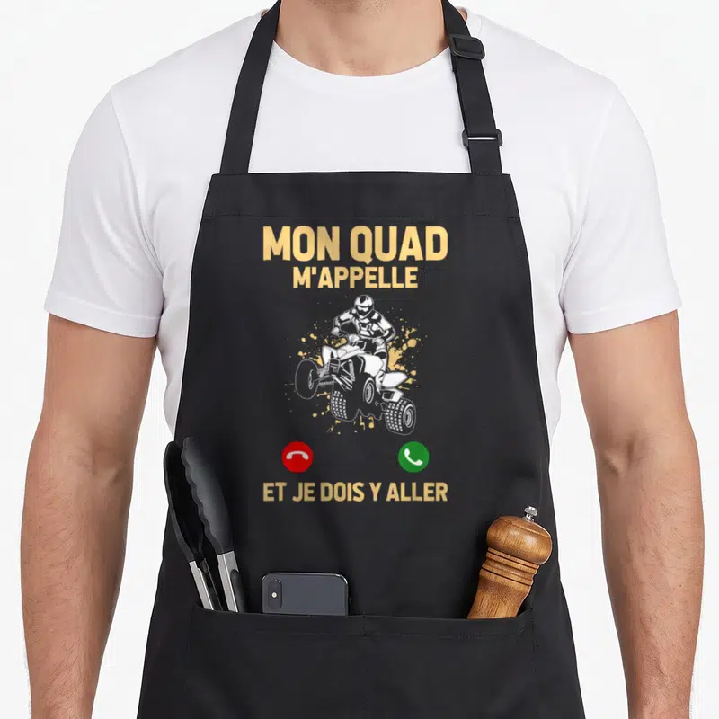 Tablier de cuisine noir avec inscription Mon Quad M'Appelle Et Je Dois Y Aller et illustration d'un pilote de quad blanc sur fond gris.