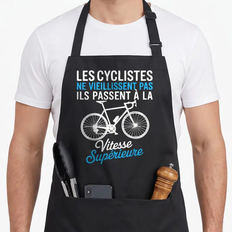 Tablier de cuisine noir avec inscription Les cyclistes ne vieillissent pas et dessin de vélo blanc et bleu.