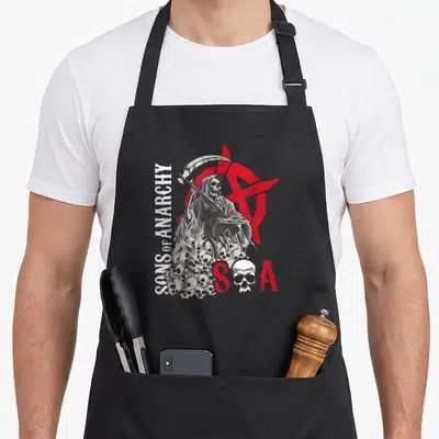 Tablier de cuisine noir avec une illustration de la Mort tenant une faucille au-dessus d'une pile de têtes et un logo S.A en rouge.
