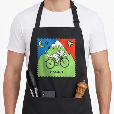 Tablier de cuisine noir avec illustration d'un cycliste blanc sur fond de montagne verte, soleil et lune colorés.