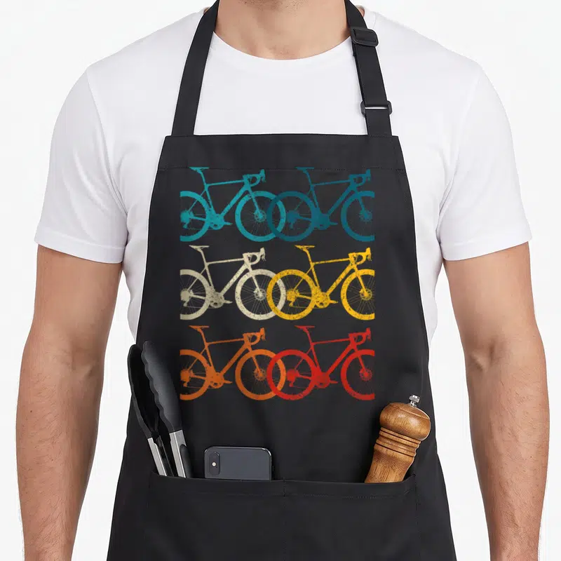 Tablier de cuisine noir orné de six silhouettes de vélos de route aux couleurs vives et effet vintage sérigraphié.