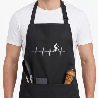 Tablier de cuisine noir avec un graphisme blanc représentant un bicrosseur sur une ligne de battement de cœur.