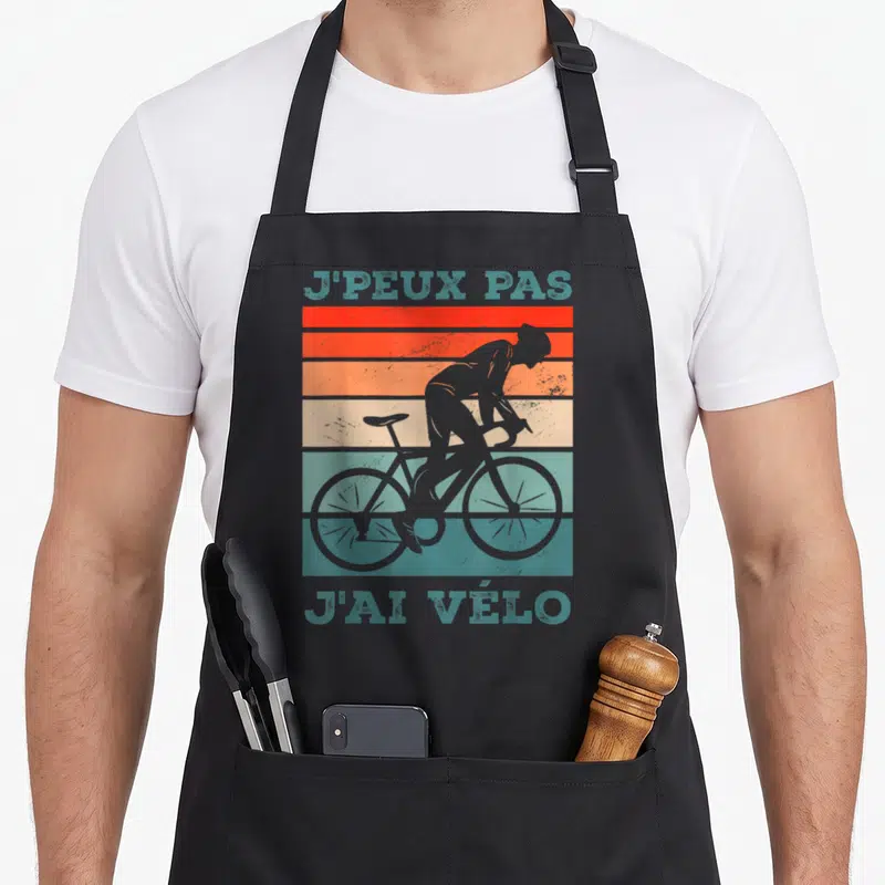 Tablier de cuisine noir avec silhouette cycliste et texte J'peux pas j'ai vélo sur fond de bandes colorées vintage.