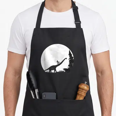 Tablier de cuisine noir avec illustration d'un cycliste VTT sur un dinosaure sous la lune