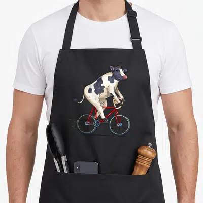Tablier de cuisine noir avec une vache cycliste biker mignonne sur un vélo rouge.
