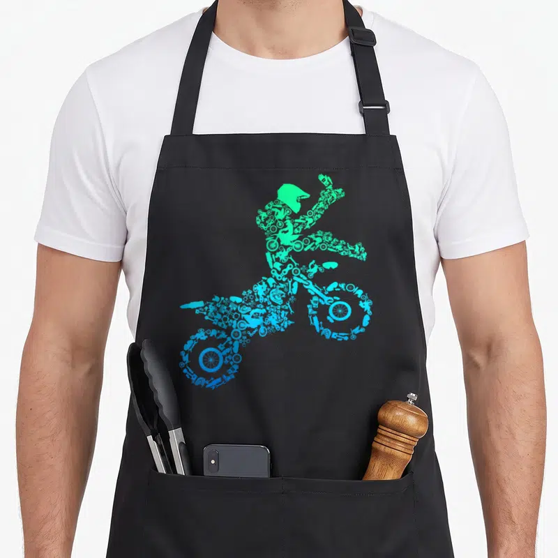 Tablier de cuisine noir avec silhouette motard motocross formée de pièces mécaniques bleues et vertes.