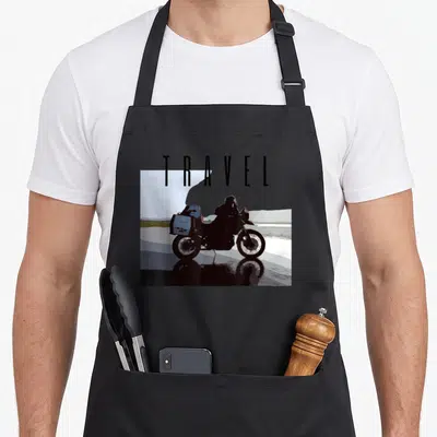 Tablier de cuisine noir avec silhouette de moto adventure et le mot TRAVEL imprimé au centre.