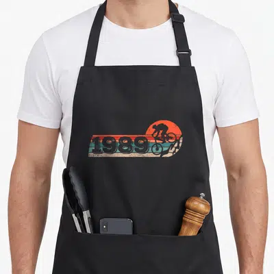 Tablier de cuisine noir avec illustration vintage 1989, cycliste orange et bandes turquoise horizontales.