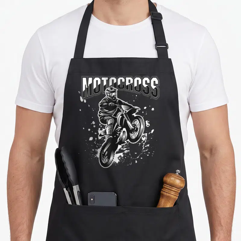 Tablier de cuisine noir avec illustration blanche d'un pilote de motocross en plein saut sous le texte MOTOCROSS.