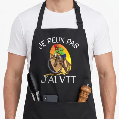 Tablier de cuisine noir avec illustration d'un cycliste et texte Je peux pas j'ai VTT imprimé en blanc.