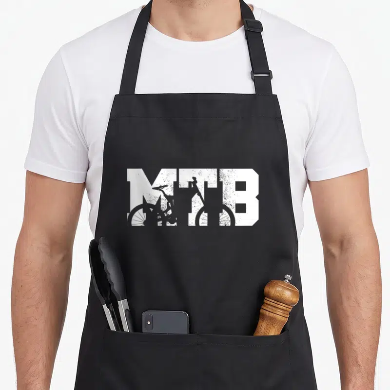Tablier de cuisine noir avec le sigle MTB blanc et une silhouette de cycliste en descente intégrée aux lettres.