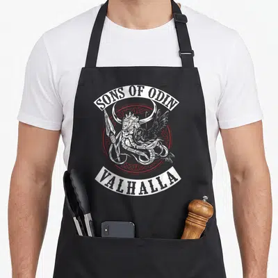 Tablier de cuisine noir avec illustration d'un guerrier viking cornu tenant une hache et un corbeau, encadré par le texte Sons of Odin Valhalla.