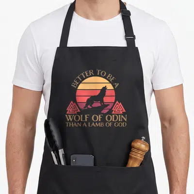Tablier de cuisine noir avec silhouette de loup devant un soleil rayé et inscriptionBetter To Be A Wolf Of Odin