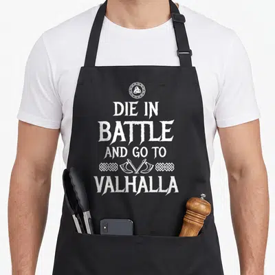 Tablier de cuisine noir avec inscription Die in battle and go to Valhalla et deux haches croisées en blanc.