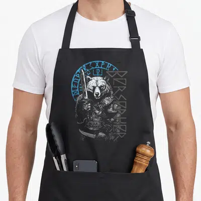 Tablier de cuisine noir avec illustration d'un ours berserker tenant une lame et des runes nordiques.