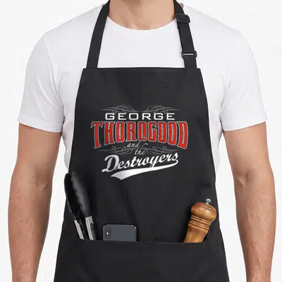 Tablier de cuisine noir avec l'inscription George Thorogood and the Destroyers en rouge et blanc sur fond uni.