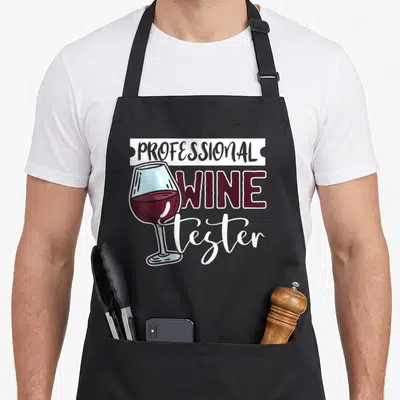 Tablier de cuisine noir avec illustration d'un verre de vin rouge et le texte Professional Wine Tester en typographie mixte.