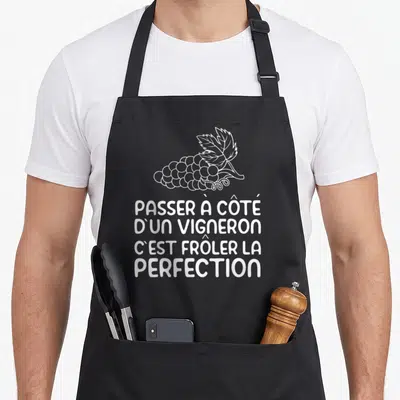 Tablier de cuisine noir avec inscription blanche Passer à côté d'un vigneron et illustration de grappe de raisin stylisée.