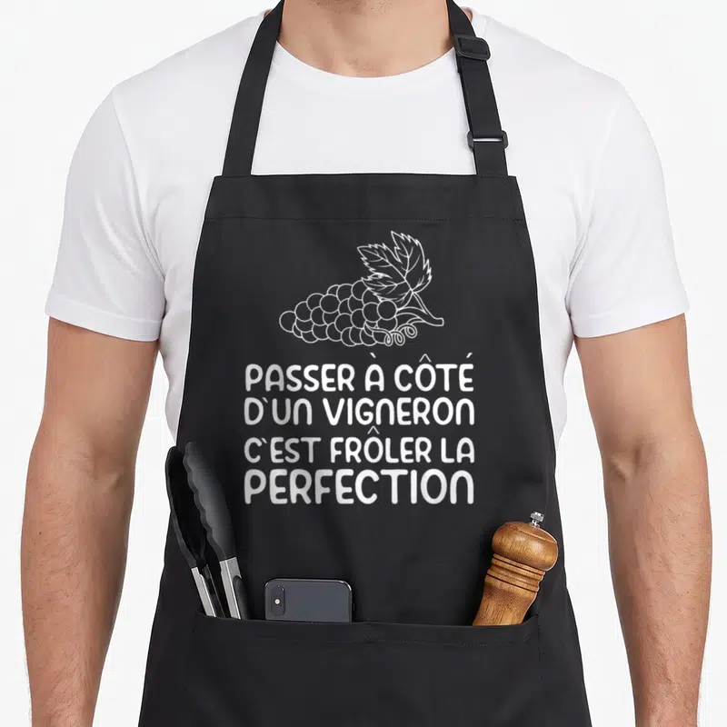 Tablier de cuisine noir avec inscription blanche Passer à côté d'un vigneron et illustration de grappe de raisin stylisée.