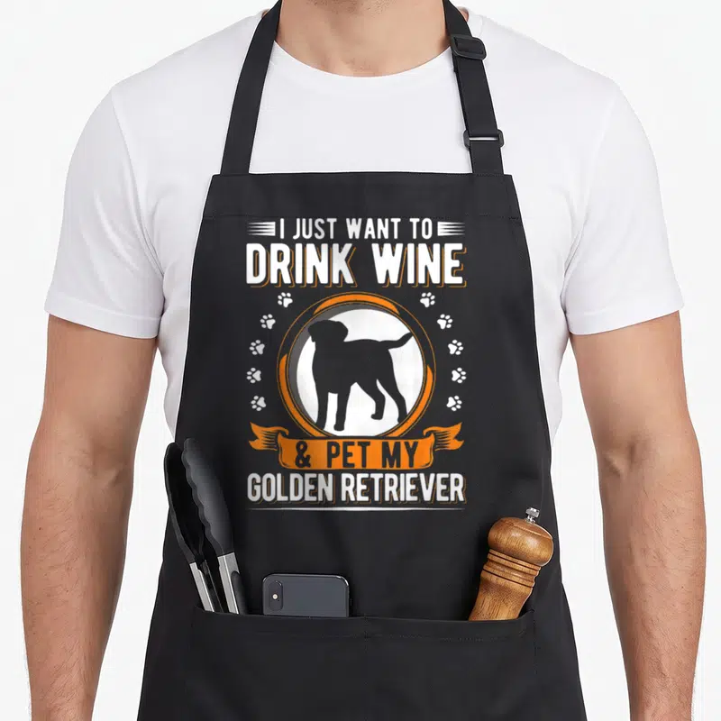 Tablier de cuisine noir avec silhouette de chien, traces de pattes et texte blanc et orange.
