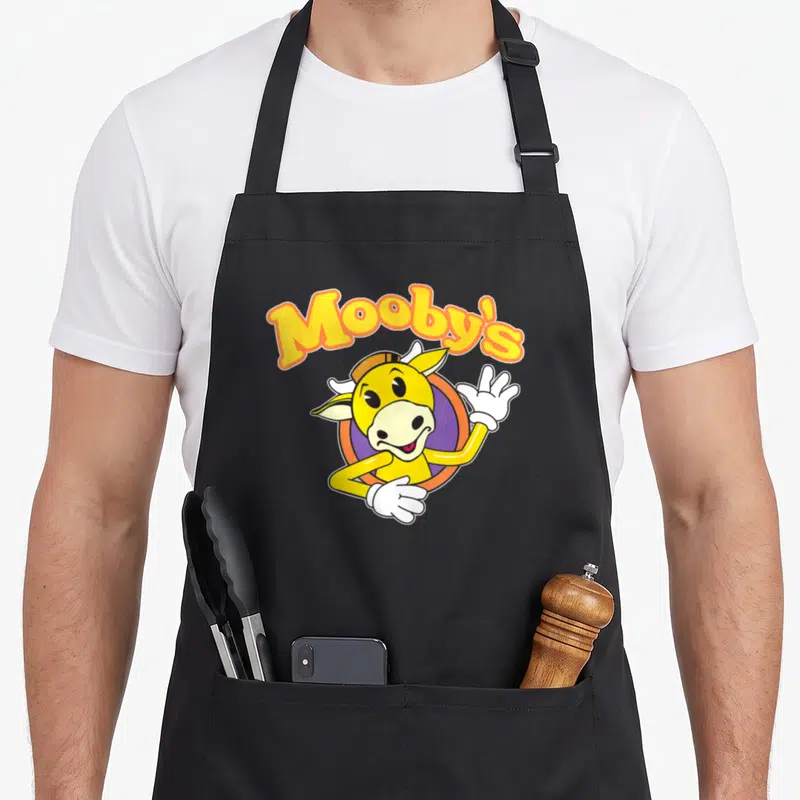 Tablier de cuisine noir avec le logo Mooby's et un mascot cow-boy jaune souriant