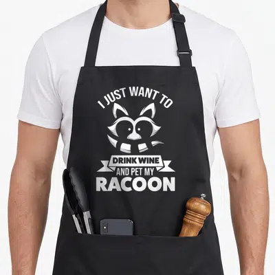 Tablier de cuisine noir avec illustration d'un raton laveur et texte blanc I just want to drink wine and pet my racoon.