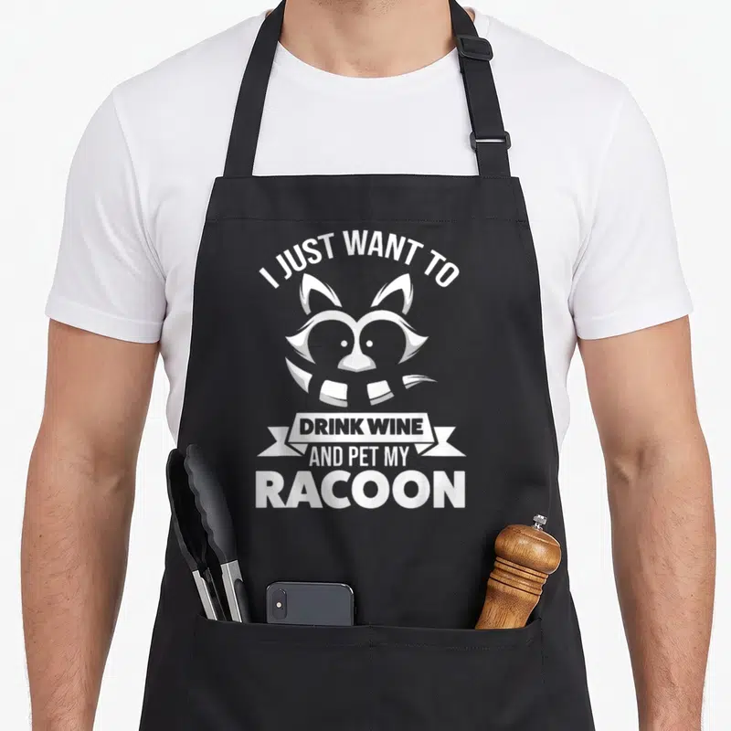 Tablier de cuisine noir avec illustration d'un raton laveur et texte blanc I just want to drink wine and pet my racoon.