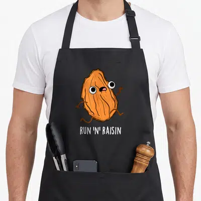 Tablier de cuisine noir avec un raisin orange courant et le texte Run 'n' Raisin imprimé en blanc.