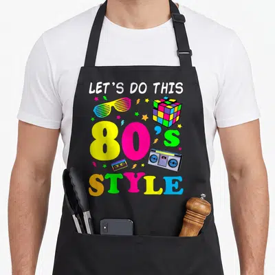 Tablier de cuisine noir avec illustration 80s Style Let's Do This, boombox, cube de Rubik et lunettes à fentes colorées.