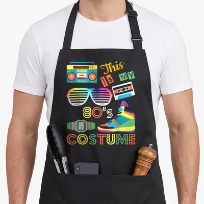 Tablier de cuisine noir avec une boombox, des lunettes à rayures, une cassette et le texte This is My 80s Costume en couleurs vives.