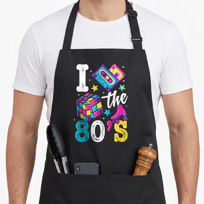 Tablier de cuisine noir avec illustration I the 80's, cassettes audio, cube de Rubik et patins roses aux couleurs vives.